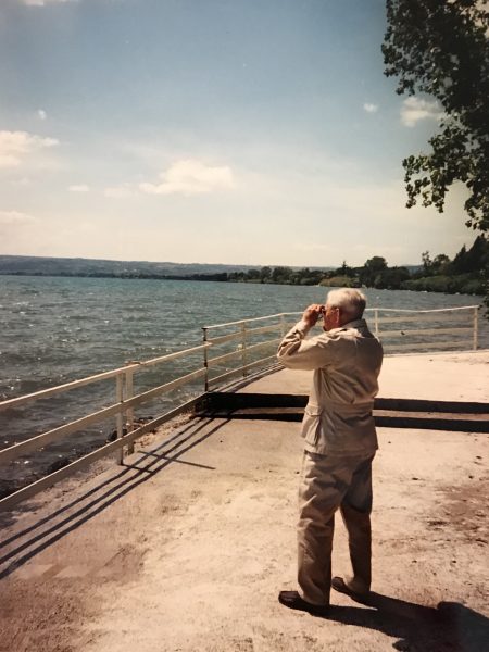 Man looking through binoculars at the water