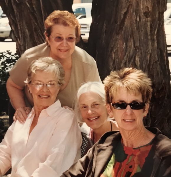 four women sitting near a tree